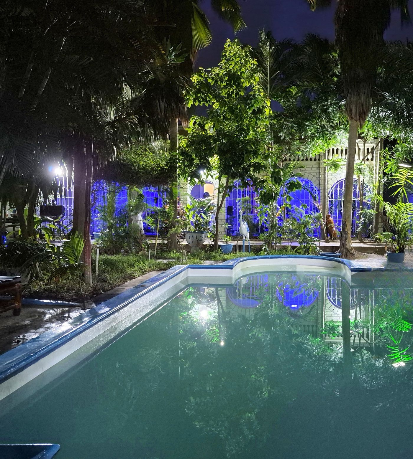 The pool at night with the lit arches of the Main House